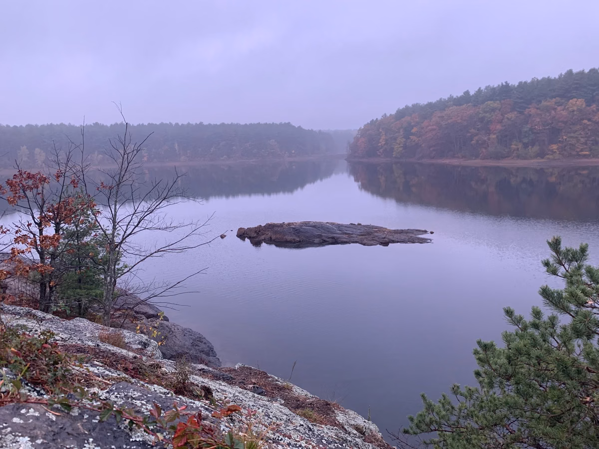 Fog over a still reservoir with fall color on the far shore, Middlesex Fells, Stoneham
